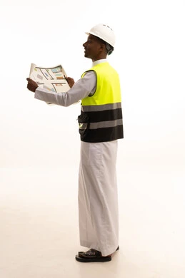 الإعمار بسواعد أبناء الوطن، مفهوم الهندسة والانشاءات المعمارية، الاحتراف فى التخطيط، المتابعة والإشراف على العمل بشكل مباشر،بورتريه لمهندس عربي خليجي سعودي اسمر يرتدي الثوب التقليدي والسترة الخاصة وخوذة الحماية يقف وبيده مخطط هندسي ، الجسم بالطول الكامل، خلفية بيضاء