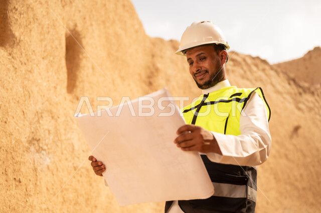 Learn about ancient architecture, the anniversary of the founding of the first Saudi state on February 22, a Saudi Gulf Arab engineer wearing a jacket and helmet holding a building plan, a tour of the popular neighborhood, the basics of building heritage houses and palaces, the day we began in 1727 AD, National Day on September 23