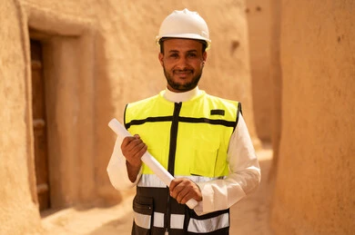 Learn about ancient architecture, the anniversary of the founding of the first Saudi state on February 22, a Saudi Gulf Arab engineer wearing a jacket and helmet holding a building plan, a tour of the popular neighborhood, the basics of building heritage houses and palaces, the day we began in 1727 AD, National Day on September 23