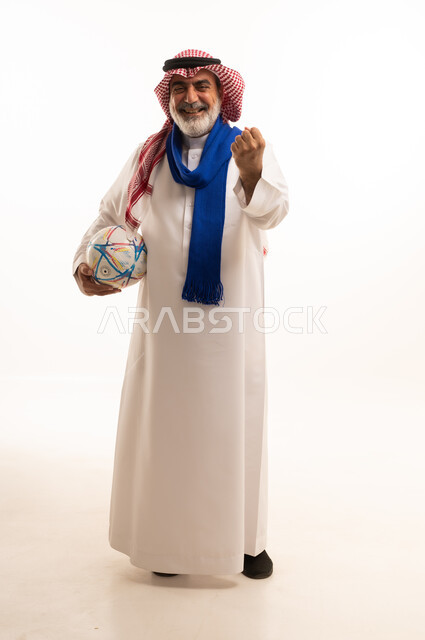 الفوز والربح والانتصار، الحماس والتفاعل مع المنتخب، بورتريه لرجل كبير السن عربي خليجي سعودي يرتدي الشماغ والثوب التقليدي يضع الوشاح يحمل بيده كرة القدم، أنديه رياضية مختلفة، الجسم بالطول الكامل، خلفية بيضاء