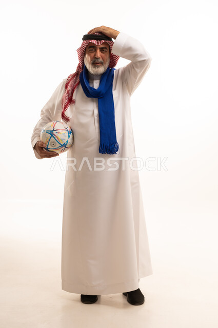 إيماءات الخسارة والفشل، الحماس والتفاعل مع المنتخب، بورتريه لرجل كبير السن عربي خليجي سعودي يرتدي الشماغ والثوب التقليدي يضع الوشاح يحمل بيده كرة القدم، أنديه رياضية مختلفة، الجسم بالطول الكامل، خلفية بيضاء