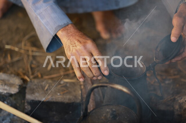 صورة لرجل عربي خليجي سعودي  يقوم باعداد الشاي والقهوة على النار ،حرق اخشاب الاشجار ، رحلات برية ، الحياة البرية في المملكة العربية السعودية