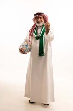 الفوز والربح والانتصار، الحماس والتفاعل مع المنتخب، بورتريه لرجل كبير السن عربي خليجي سعودي يرتدي الشماغ والثوب التقليدي يضع الوشاح يحمل بيده كرة القدم، أنديه رياضية مختلفة، الجسم بالطول الكامل، خلفية بيضاء