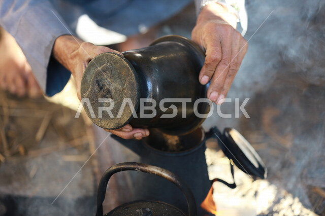 صورة لرجل عربي خليجي سعودي  يقوم باعداد الشاي والقهوة على النار ،حرق اخشاب الاشجار ، رحلات برية ، الحياة البرية في المملكة العربية السعودية