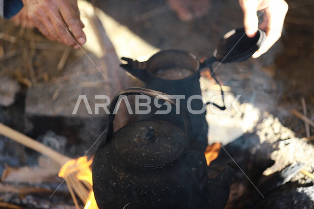 صورة لرجل عربي خليجي سعودي  يقوم باعداد الشاي والقهوة على النار ،حرق اخشاب الاشجار ، رحلات برية ، الحياة البرية في المملكة العربية السعودية