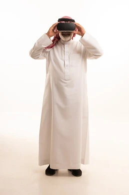 قضاء أوقات ممتعة ومسلية بالألعاب الافتراضية، الاستمتاع بمشاهدة أفلام الواقع الافتراضي، بورتريه لرجل عربي خليجي سعودي كبير بالسن يرتدي الثوب التقليدي و الشماغ يضع نظارة الواقع الافتراضي ثلاثية الابعاد، الجسم بالطول الكامل، خلفية بيضاء