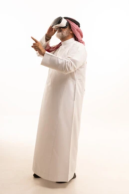 قضاء أوقات ممتعة ومسلية بالألعاب الافتراضية، الاستمتاع بمشاهدة أفلام الواقع الافتراضي، بورتريه لرجل عربي خليجي سعودي كبير بالسن يرتدي الثوب التقليدي و الشماغ يضع نظارة الواقع الافتراضي ثلاثية الابعاد، الجسم بالطول الكامل، خلفية بيضاء