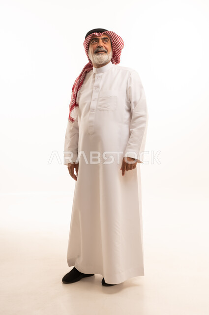 التقدم بالعمر والهيبة، بورتريه لرجل كبير بالسن عربي خليجي سعودي يرتدي الثوب التقليدي و الشماغ يقف باستقامة, الاهتمام بالأناقة والمظهر الخارجي، مفهوم الرجولة العربية, الجسم بالطول الكامل، خلفية بيضاء