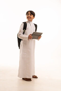 Searching for useful and important information, portrait of a Saudi Arabian Gulf boy wearing traditional dress and a backpack holding a tablet, integrating technology with learning, attending e-learning courses, full body image, white background