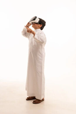 محاكاة العالم الخيالي والنظر الى الافلام الواقعيه، تعابير الاندماج والتركيز، التطور التقني والتكنولوجي، بورتريه لولد عربي خليجي سعودي يرتدي الثوب التقليدي ينظر من خلال نظارات ثلاثية الأبعاد (الفي ار),  الجسم بالطول الكامل، خلفيه بيضاء