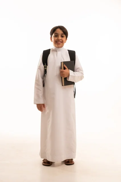 The concept of hard work to achieve success, educational scientific curricula, the concept of returning to school, a portrait of a Saudi Arabian Gulf student wearing traditional clothing, carrying a school backpack and holding a book in his hand, a full body image, a white background