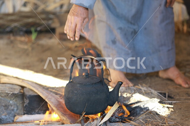صورة لرجل عربي خليجي سعودي  يقوم باعداد الشاي والقهوة على النار ،حرق اخشاب الاشجار ، رحلات برية ، الحياة البرية في المملكة العربية السعودية