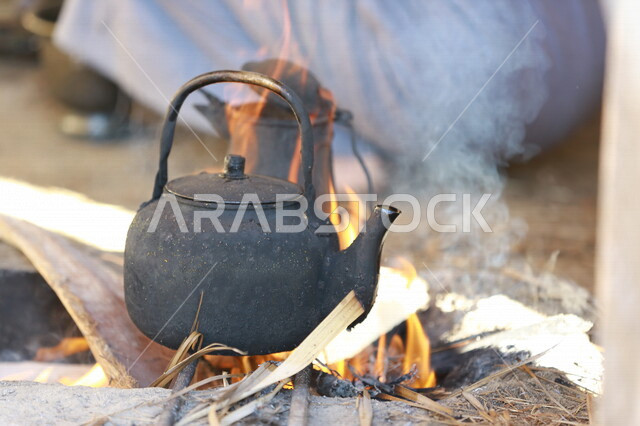 صورة لرجل عربي خليجي سعودي  يقوم باعداد الشاي والقهوة على النار ،حرق اخشاب الاشجار ، رحلات برية ، الحياة البرية في المملكة العربية السعودية