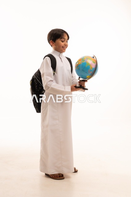 الاهتمام بدراسة العلوم الجغرافية، توسيع الآفاق وفهم التنوع الثقافي والطبيعي، أهمية التعليم في تطوير المجتمع السعودي، بورتريه لطالب عربي خليجي سعودي يرتدي الثوب التقليدي وحقيبة الظهر يحمل بيده مجسم الكرة الأرضية، الجسم بالطول الكامل، خلفية بيضاء