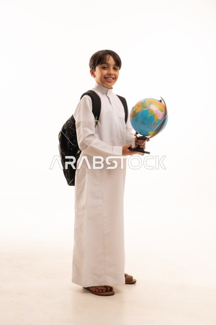 Interest in studying geographical sciences, broadening horizons and understanding cultural and natural diversity, the importance of education in developing Saudi society, portrait of a Saudi Arabian Gulf student wearing traditional thobe and backpack holding a globe, full body, white background
