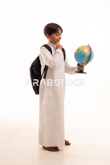 الاهتمام بدراسة العلوم الجغرافية، توسيع الآفاق وفهم التنوع الثقافي والطبيعي، أهمية التعليم في تطوير المجتمع السعودي، بورتريه لطالب عربي خليجي سعودي يرتدي الثوب التقليدي وحقيبة الظهر يحمل بيده مجسم الكرة الأرضية، الجسم بالطول الكامل، خلفية بيضاء