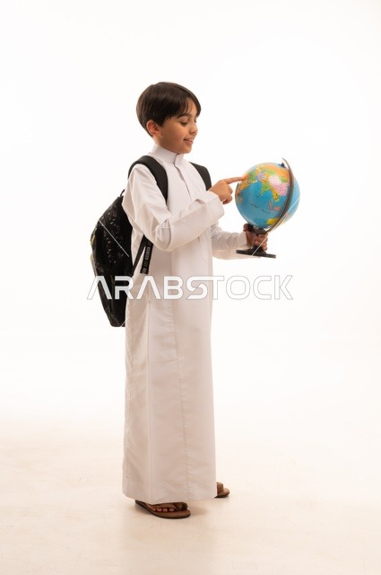 الاهتمام بدراسة العلوم الجغرافية، توسيع الآفاق وفهم التنوع الثقافي والطبيعي، أهمية التعليم في تطوير المجتمع السعودي، بورتريه لطالب عربي خليجي سعودي يرتدي الثوب التقليدي وحقيبة الظهر يحمل بيده مجسم الكرة الأرضية، الجسم بالطول الكامل، خلفية بيضاء
