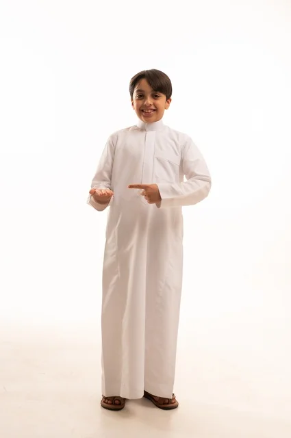 ايماءات تحديد موقع معين، حركات تدل على هذا المكان (هنا)، بورتريه لولد عربي خليجي سعودي يرتدي الثوب التقليدي ويشير باصبع السبابة الى شيء ما، صورة الجسم بالطول الكامل، خلفية بيضاء