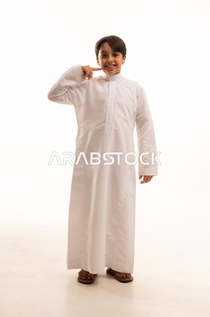 The concept of fun and play, jumping high with gestures of happiness and pleasure, portrait of a Saudi Arabian Gulf boy wearing traditional dress jumping in the air, having a fun and entertaining time, full body, white background