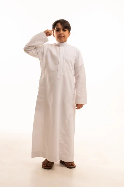 ايماءات تحديد موقع معين، حركات تدل على هذا المكان (هنا)، بورتريه لولد عربي خليجي سعودي يرتدي الثوب التقليدي ويشير باصبع السبابة الى شيء ما، صورة الجسم بالطول الكامل، خلفية بيضاء