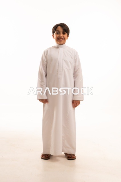 Concern for elegance and outward appearance, the concept of self-confidence, taking personal photos for official documents, portrait of a Saudi Arabian Gulf boy wearing traditional dress standing with gestures of pleasure and happiness, full body, white background