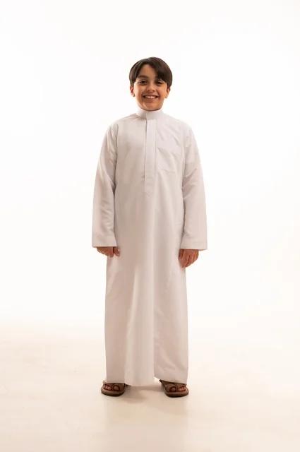 Concern for elegance and outward appearance, the concept of self-confidence, taking personal photos for official documents, portrait of a Saudi Arabian Gulf boy wearing traditional dress standing with gestures of pleasure and happiness, full body, white background