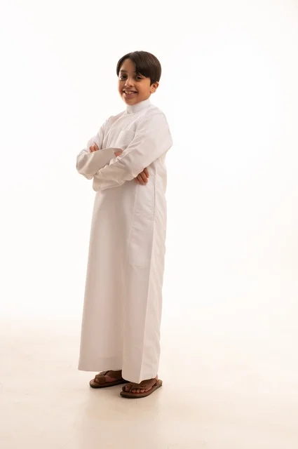 Concern for elegance and outward appearance, the concept of self-confidence, taking personal photos for official documents, portrait of a Saudi Arabian Gulf boy wearing traditional dress standing with gestures of pleasure and happiness, full body, white background