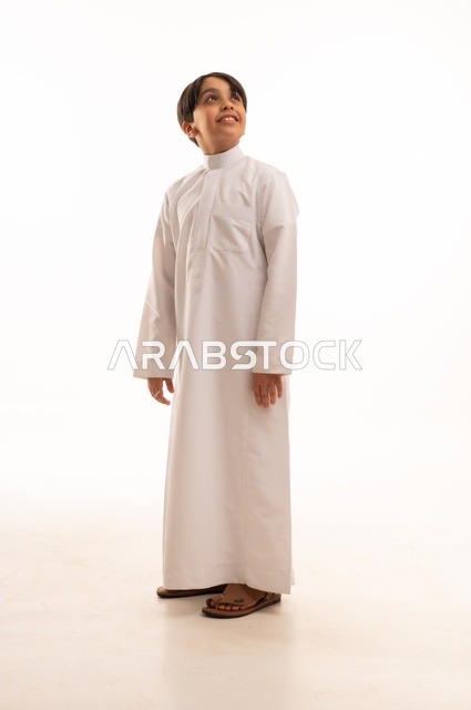 Concern for elegance and outward appearance, the concept of self-confidence, taking personal photos for official documents, portrait of a Saudi Arabian Gulf boy wearing traditional dress standing with gestures of pleasure and happiness, full body, white background