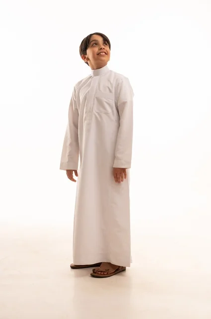 الاهتمام بالأناقة والمظهر الخارجي، مفهوم الثقة بالنفس، التقاط الصور الشخصية للوثائق الرسمية، بورتريه لولد عربي خليجي سعودي يرتدي الثوب التقليدي يقف بإيماءات السرور والسعادة، الجسم بالطول الكامل، خلفية بيضاء