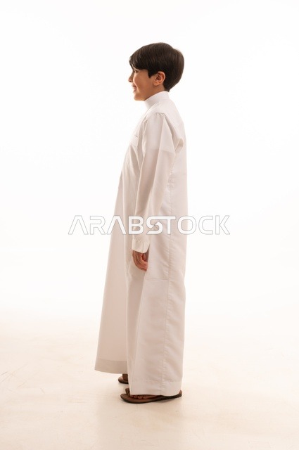 Concern for elegance and outward appearance, the concept of self-confidence, taking personal photos for official documents, portrait of a Saudi Arabian Gulf boy wearing traditional dress standing with gestures of pleasure and happiness, full body, white background