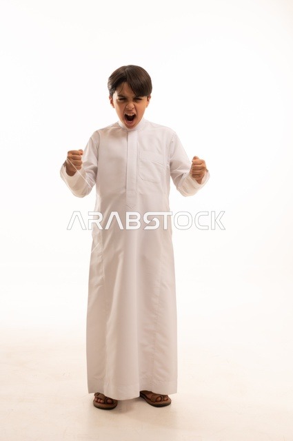 النداء بصوت مرتفع، بورتريه لولد عربي خليجي سعودي يرتدي الثوب التقليدي يرفع قبضتي يديه للأعلى، إيماءات المناداة لشخص ما، الصراخ والتكلم بنبرة عالية للسماع بشكل جيد، محادثات وتواصل اجتماعي الجسم بالطول الكامل، خلفية بيضاء