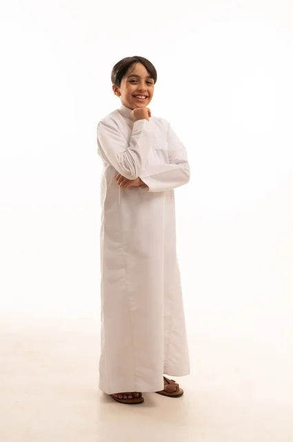 الاهتمام بالأناقة والمظهر الخارجي، مفهوم الثقة بالنفس، التقاط الصور الشخصية للوثائق الرسمية، بورتريه لولد عربي خليجي سعودي يرتدي الثوب التقليدي يقف بإيماءات السرور والسعادة، الجسم بالطول الكامل، خلفية بيضاء