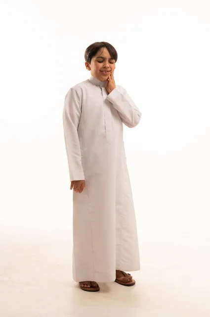 تسوس الأضراس وإلتهاب اللثه ,وجع الأسنان والحاجه لزيارة الطبيب، طلب العلاج والمساعده، بورتريه لولد عربي خليجي سعودي يرتدي الثوب التقليدي يضع يده على فمه، صورة الجسم بالطول الكامل، خلفية بيضاء