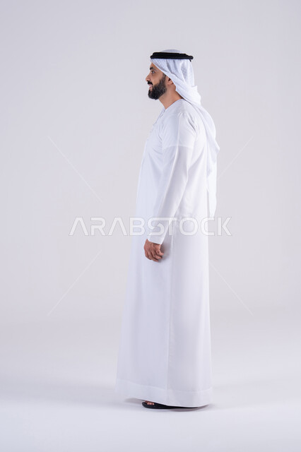 تعابير السرور والسعاده ، مفهوم الرجوله والقوه، الاهتمام بالاناقة والاهتمام بالمظهر الخارجي، بورتريه من الجانب لرجل عربي خليجي اماراتي يرتدي الكندوره  والغتره، يقف بإيماءات الثقة بالنفس