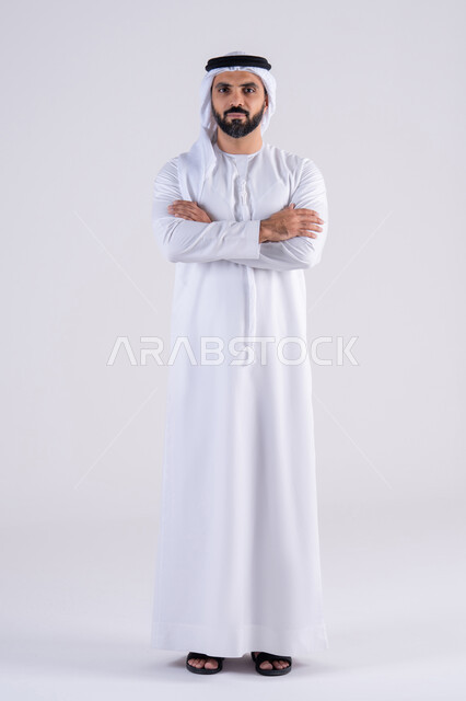 الاهتمام بالاناقة والاهتمام بالمظهر الخارجي، مفهوم الرجوله والقوه، بورتريه لرجل عربي خليجي اماراتي يرتدي الكندوره  والغتره، يقف بايدى متقاطعه وإيماءات الثقة بالنفس