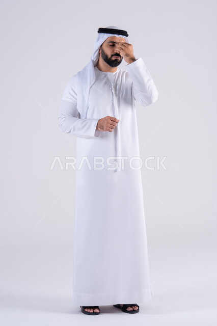 القلق والحيرة في اتخاذ القرار الصحيح، التفكير بعمق وشرود الذهن، محاولة إيجاد حل للمشكلات الصعبة، بورتريه لرجل عربي خليجي اماراتي يرتدي الكندوره والغتره، يضع يده على  وجهه بإيماءات الحيرة