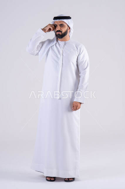 القلق والحيرة في اتخاذ القرار الصحيح، التفكير بعمق وشرود الذهن، محاولة إيجاد حل للمشكلات الصعبة، بورتريه لرجل عربي خليجي اماراتي يرتدي الكندوره والغتره، يضع يده على  وجهه بإيماءات الحيرة