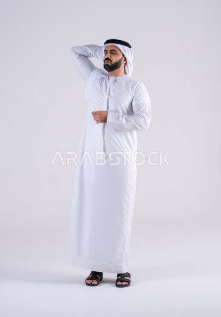 الشعور بالمرض وألم الرأس, آلام الشقيقة والصداع النصفي، الحاجه إلى العلاج والمساعده,بورتريه لرجل عربي خليجي اماراتي يرتدي الكندوره والغتره يضع يديه على رأسه بإيماءات الانزعاج والتعب