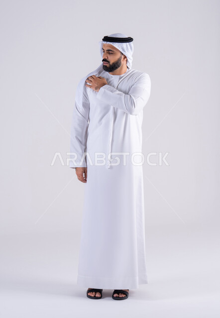 الإحساس بوجع في عضلات الكتف، الحاجة للعلاج والذهاب للطبيب, الشعور بالتعب والإرهاق, آلام العظام والمفاصل, بورتريه لرجل عربي خليجي اماراتي يرتدي الكندوره والغتره يضع يده على كتفه بتعابير الألم