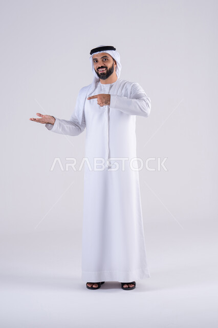 تعابير تحدد هذا المكان هنا،بورتريه لرجل عربي خليجي اماراتي يرتدي الكندوره والغتره، يشير بإصبع السبابة  جانباً إلى شيء ، النظر إلى الكاميرا بإيماءات الفرح والسرور، تحديد موقع معين