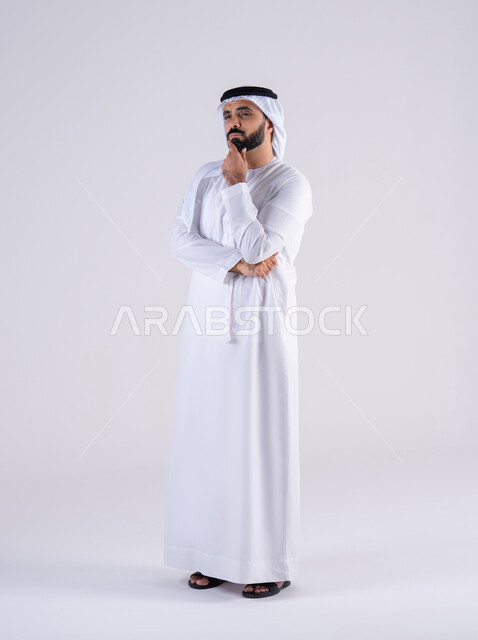 محاولة إيجاد حل للمشكلات الصعبة، القلق والحيرة في اتخاذ القرار الصحيح، التفكير بعمق وشرود الذهن،  بورتريه لرجل عربي خليجي اماراتي يرتدي الكندوره والغتره، يضع يده على  وجهه بإيماءات الحيرة