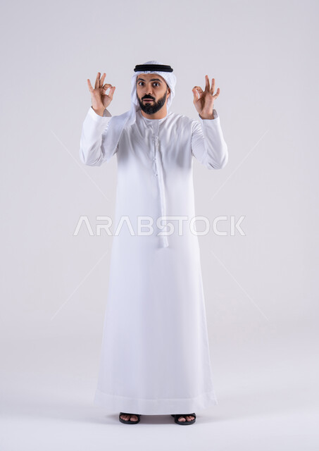 تعابير الرضي والموافقة ،البشاشة والشعور بالسعادة،  بورتريه لرجل عربي خليجي اماراتي يرتدي الكندوره والغتره،يقوم برفع ايديه بإيماءات الجودة والامتياز والتميز ، التعبير عن الجودة والاتقان