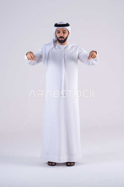 تحديد موقع معين، النظر بإيماءات التركيز ، تعابير تحدد هذا المكان هنا، بورتريه لرجل عربي خليجي اماراتي يرتدي الكندوره  والغتره، يشير بإصبع السبابة إلى الاسفل
