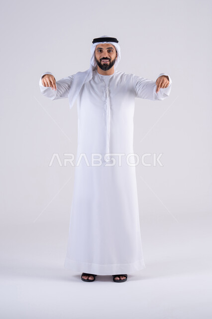 تعابير تحدد هذا المكان هنا، تحديد موقع معين، النظر بإيماءات التركيز ، بورتريه لرجل عربي خليجي اماراتي يرتدي الكندوره  والغتره، يشير بإصبع السبابة إلى الاسفل