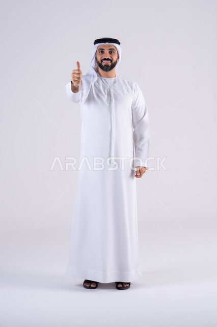البشاشة والشعور بالسعادة،  تعابير الرضي والموافقة ، بورتريه لرجل عربي خليجي اماراتي يرتدي الكندوره والغتره،يقوم برفع ايديه بإيماءات الجودة والامتياز والتميز ، التعبير عن الجودة والاتقان