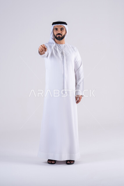 تحديد موقع معين، تعابير تحدد هذا المكان هنا،النظر بإيماءات التركيز ، بورتريه لرجل عربي خليجي اماراتي يرتدي الكندوره  والغتره، يشير بإصبع السبابة إلى الكاميرا
