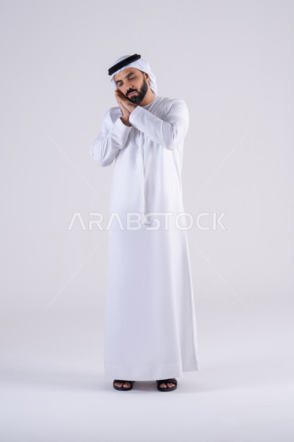 الشعور بالتعب و الحاجه الى الراحه, الإحساس بالكسل والخمول، بورتريه لرجل عربي خليجي اماراتي يرتدي الكندوره والغتره يضع يديه على وجهه بإيماءات النوم، تعابير النعاس والإرهاق