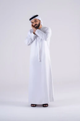 Feeling tired and in need of rest. Feeling lazy and lethargic. Portrait of an Emirati Gulf Arab man wearing a kandura and ghutra, placing his hands on his face in gestures of sleep. Expressions of drowsiness and exhaustion.