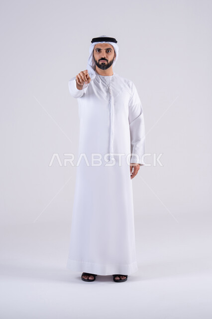 تعابير تحدد هذا المكان هنا، تحديد موقع معين، النظر بإيماءات التركيز ، بورتريه لرجل عربي خليجي اماراتي يرتدي الكندوره  والغتره، يشير بإصبع السبابة إلى الكاميرا