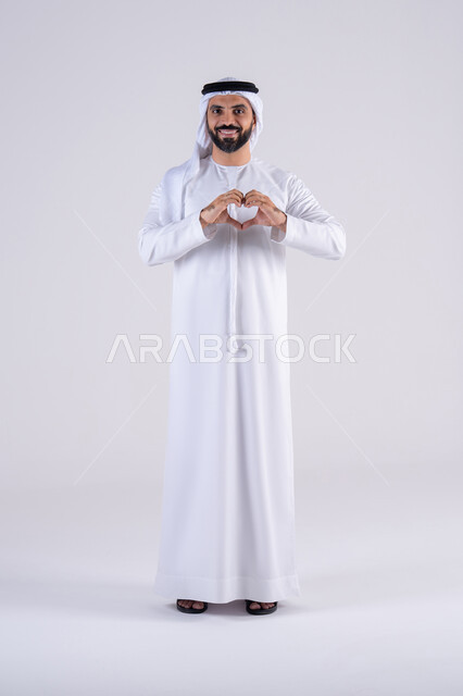 ايماءات يدين على شكل قلب، اظهار مشاعر الحب والشغف، مفهوم المحبة والمودة،  بورتريه لرجل عربي خليجي اماراتي يرتدي الكندوره والغتره ينظر إلى الكاميرا بتعابير السرور والسعادة
